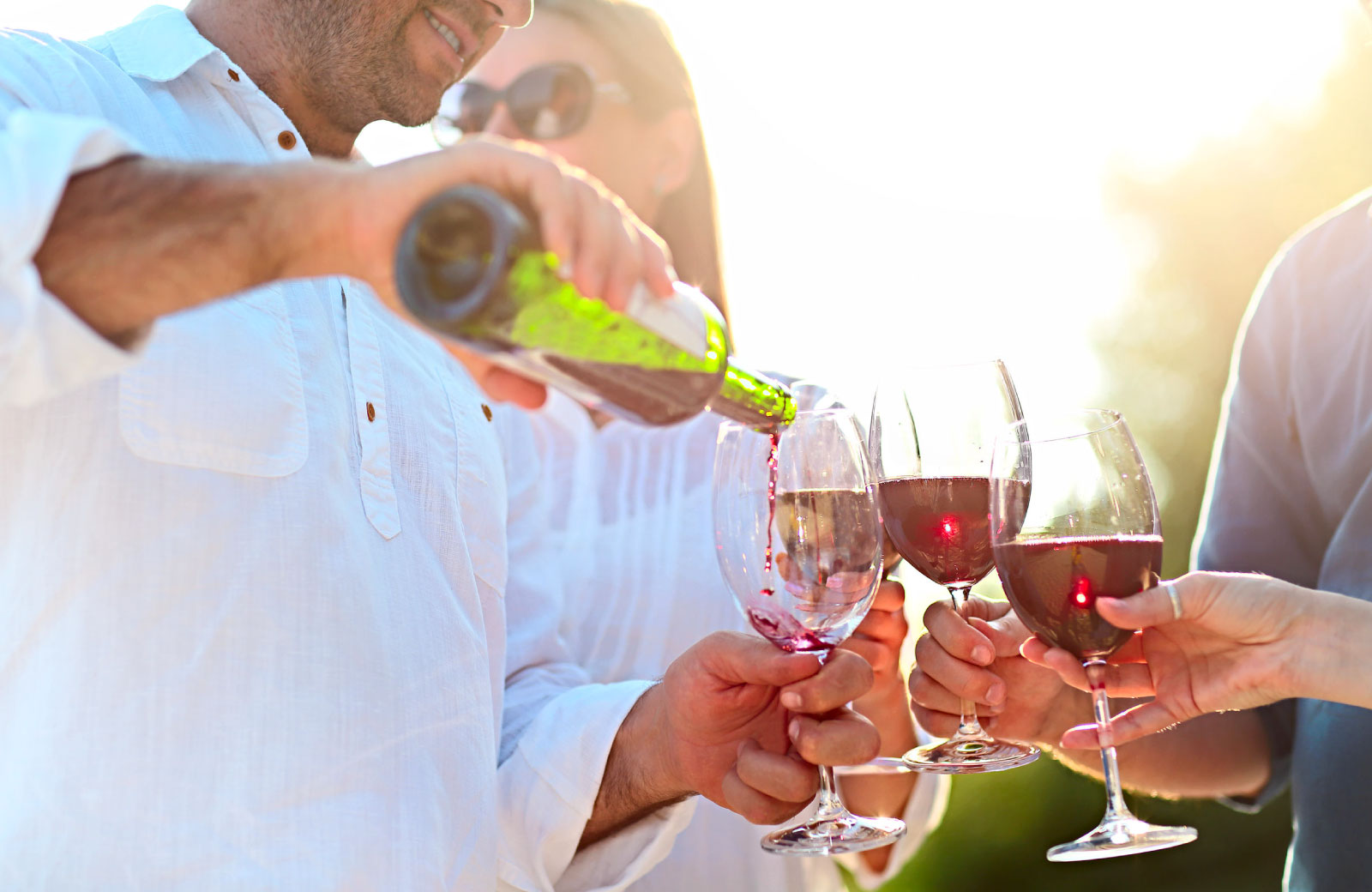 man pouring red wine in wine glasses