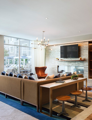Lounge area with a sectional couch, armchair, table seating, and a TV mounted above a linear fireplace.
