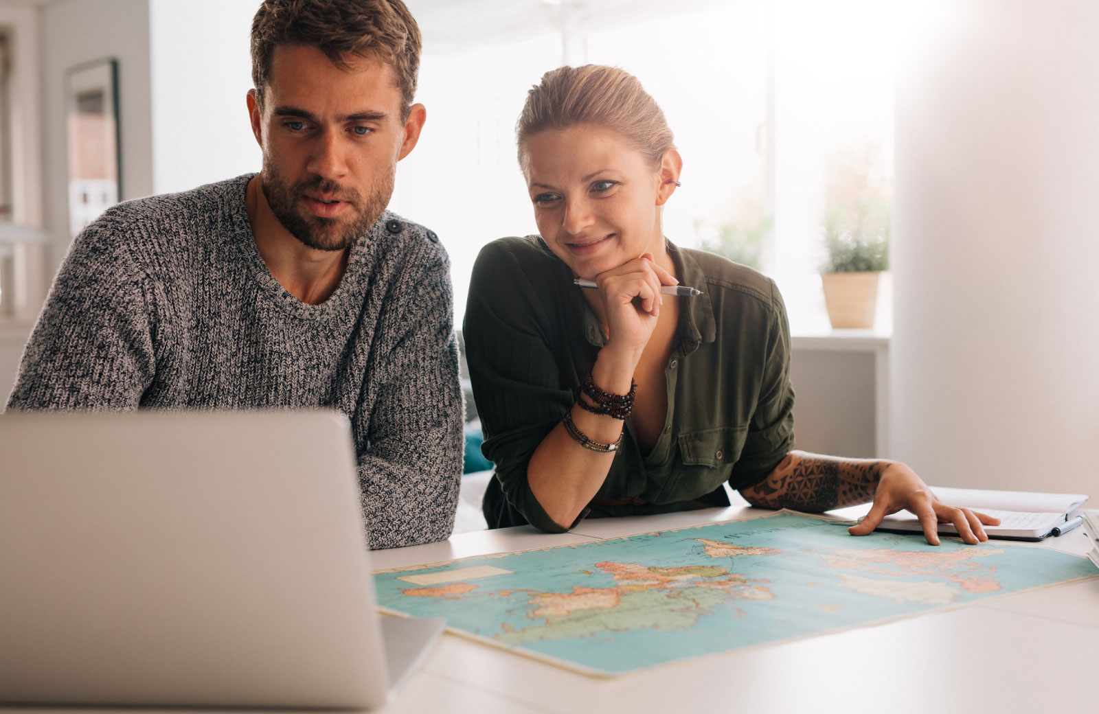 couple looking at a laptop with map on the table