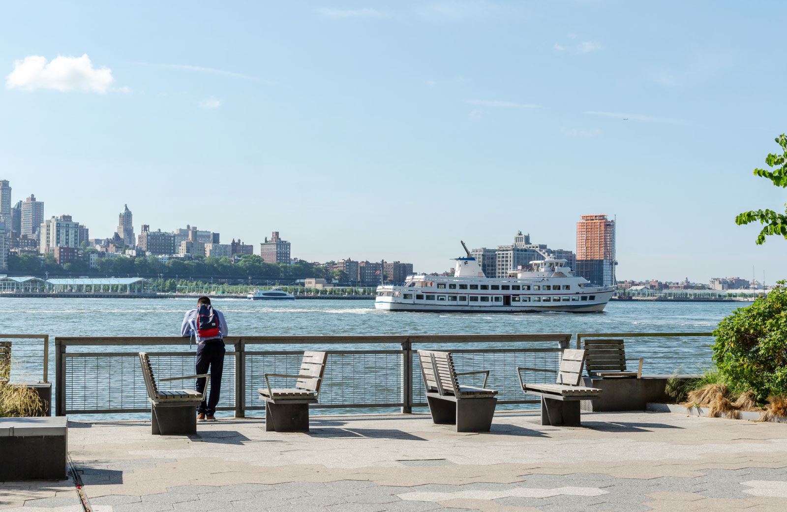 man standing behind a rail with moving ferry on the foreground