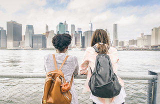 two girls looking at the cityscape from the harbor