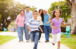 A multigenerational family on a walk, with two running children leading the group