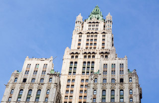 An upward angle shot of the Woolworth Building against a blue sky.