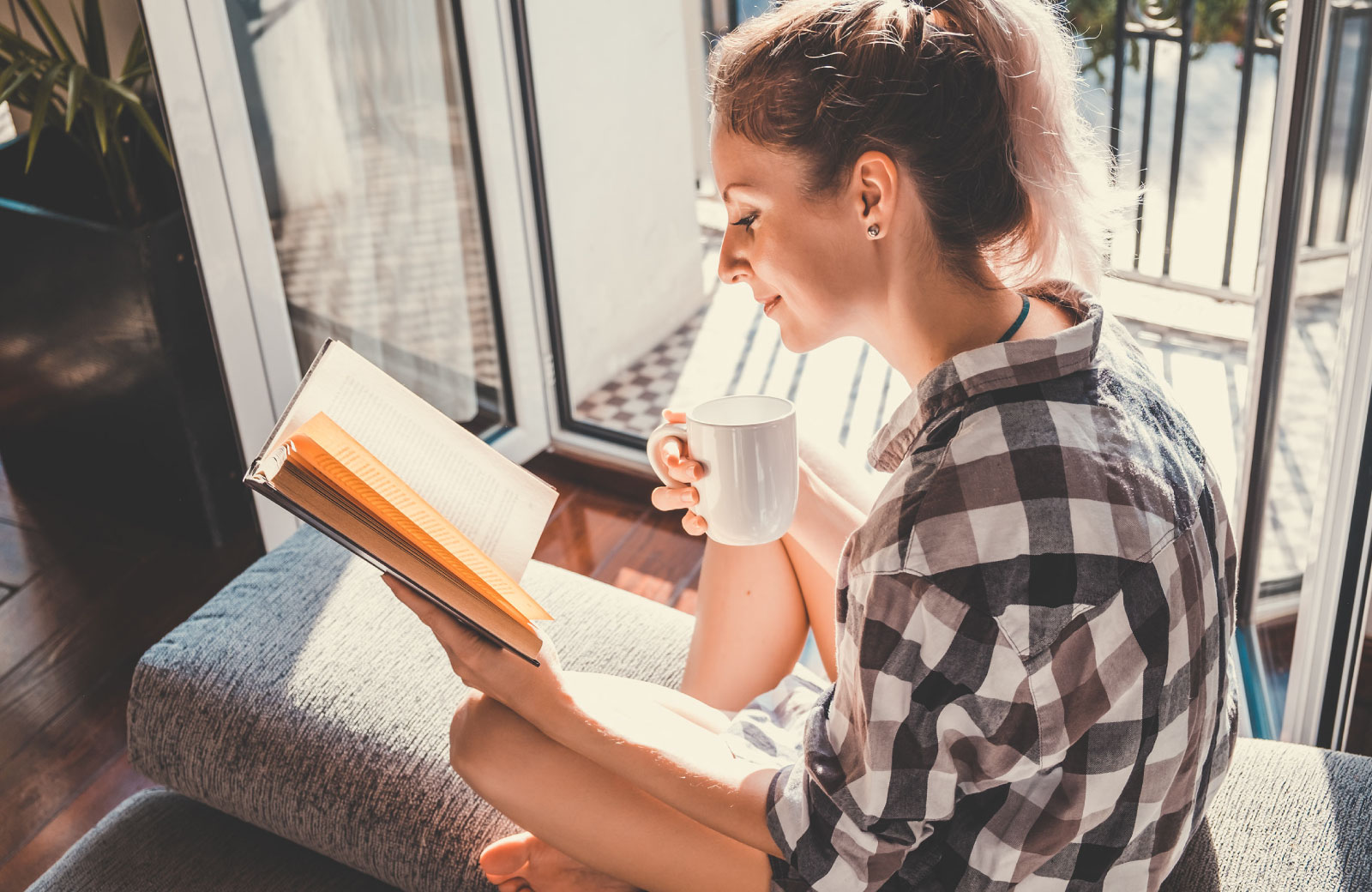 girl reading a book with mug in hand