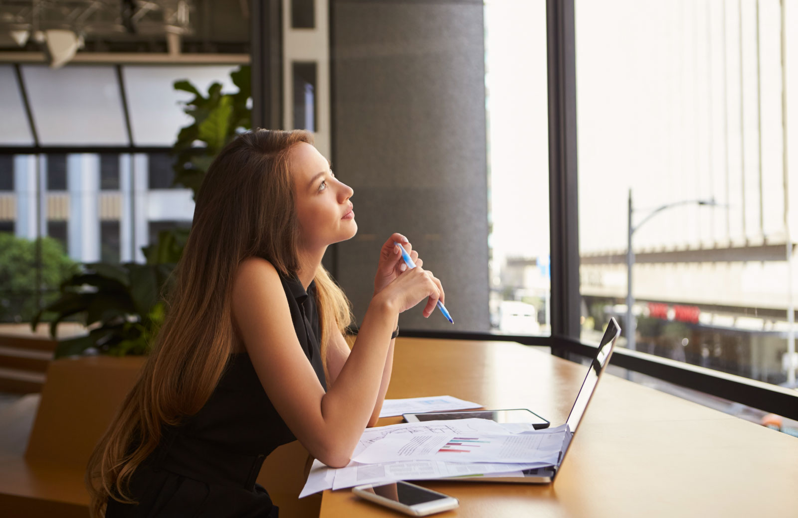 young woman looking up with laptop in front