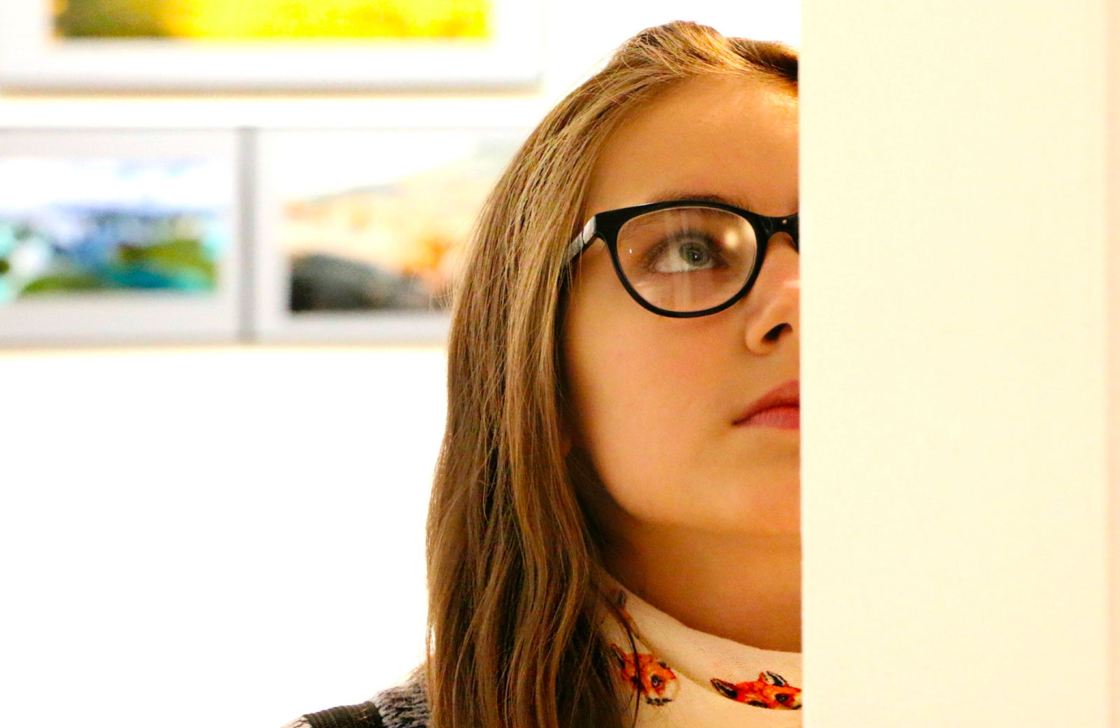 woman with glasses examining a painting closely