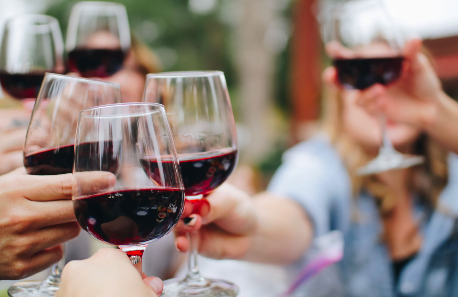 people toasting glasses with red wine