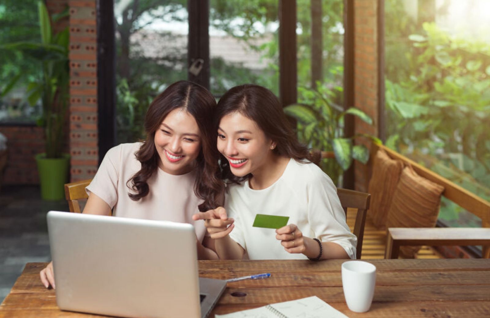 two girls shopping online holding credit card