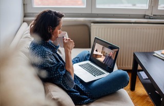 Woman sitting casually on a couch with an open laptop on her lap