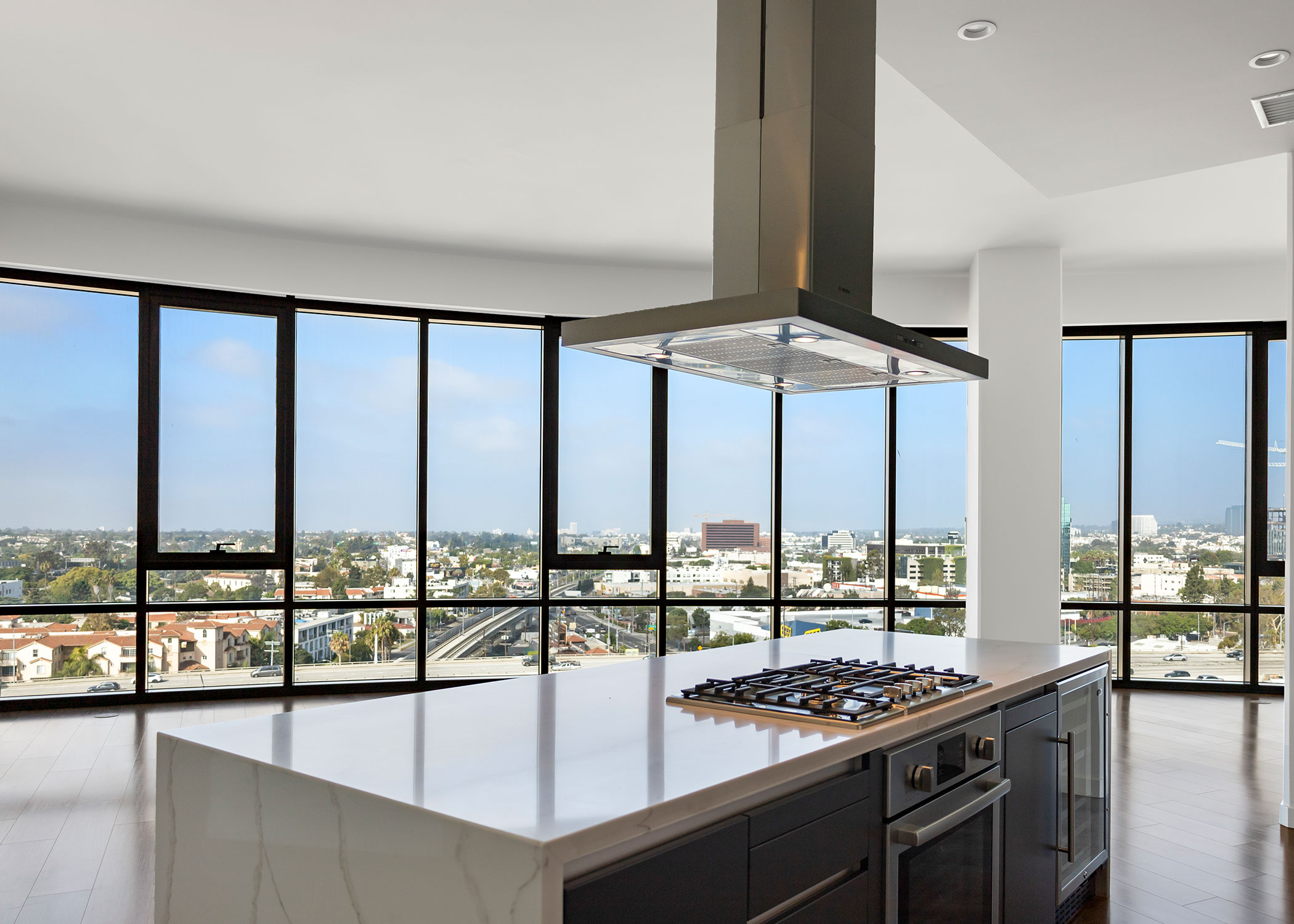 Penthouse kitchen island with views of living room and floor to ceiling windows