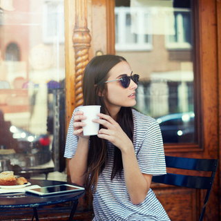A woman drinking a latte outside a cafe
