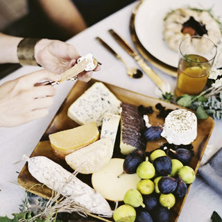 A close up of a cheese platter with soft and hard cheeses and fresh figs