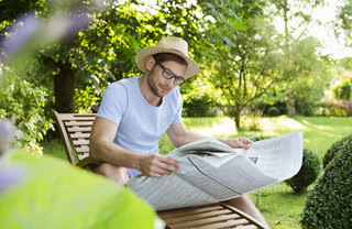 A man reading a newspaper in a grassy park