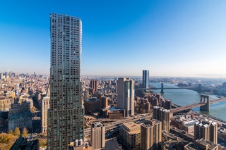 Aerial view of the 19 Dutch building towering above other buildings in the Financial District, set against a blue sky.