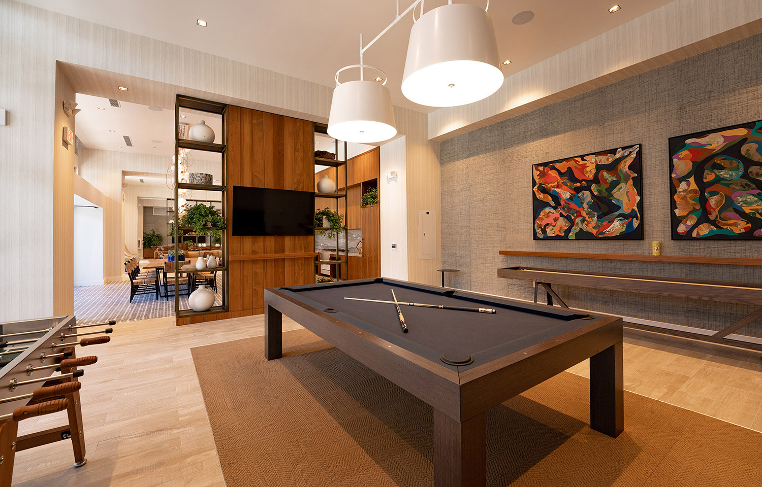 Two pieces of artwork mounted on the wall with a shuffle board table right in front.