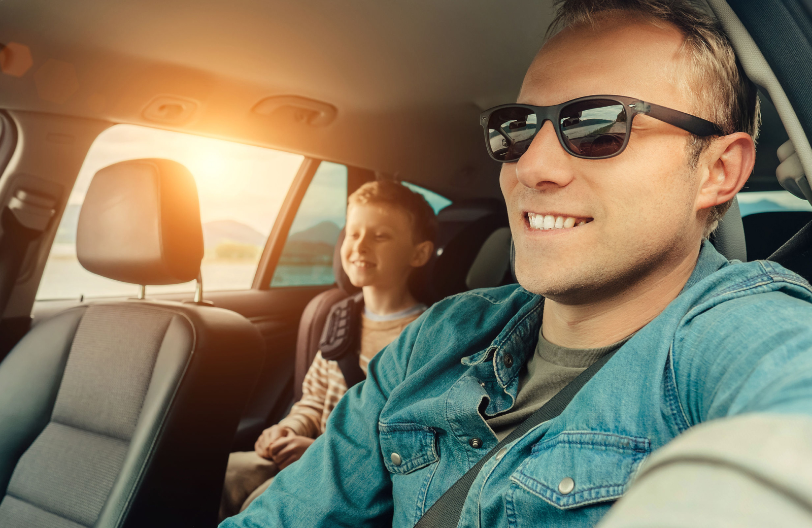 dad in sunglasses driving a car with son in the backseat on a road trip - 15 Cliff blog post