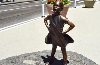 Fearless Girl, a four-foot bronze statue of a young girl, standing boldly with her head tilted up and her hands on her hips.
