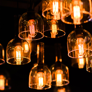 Close-up of hanging glass pendants with Edison bulbs lit against a black background.