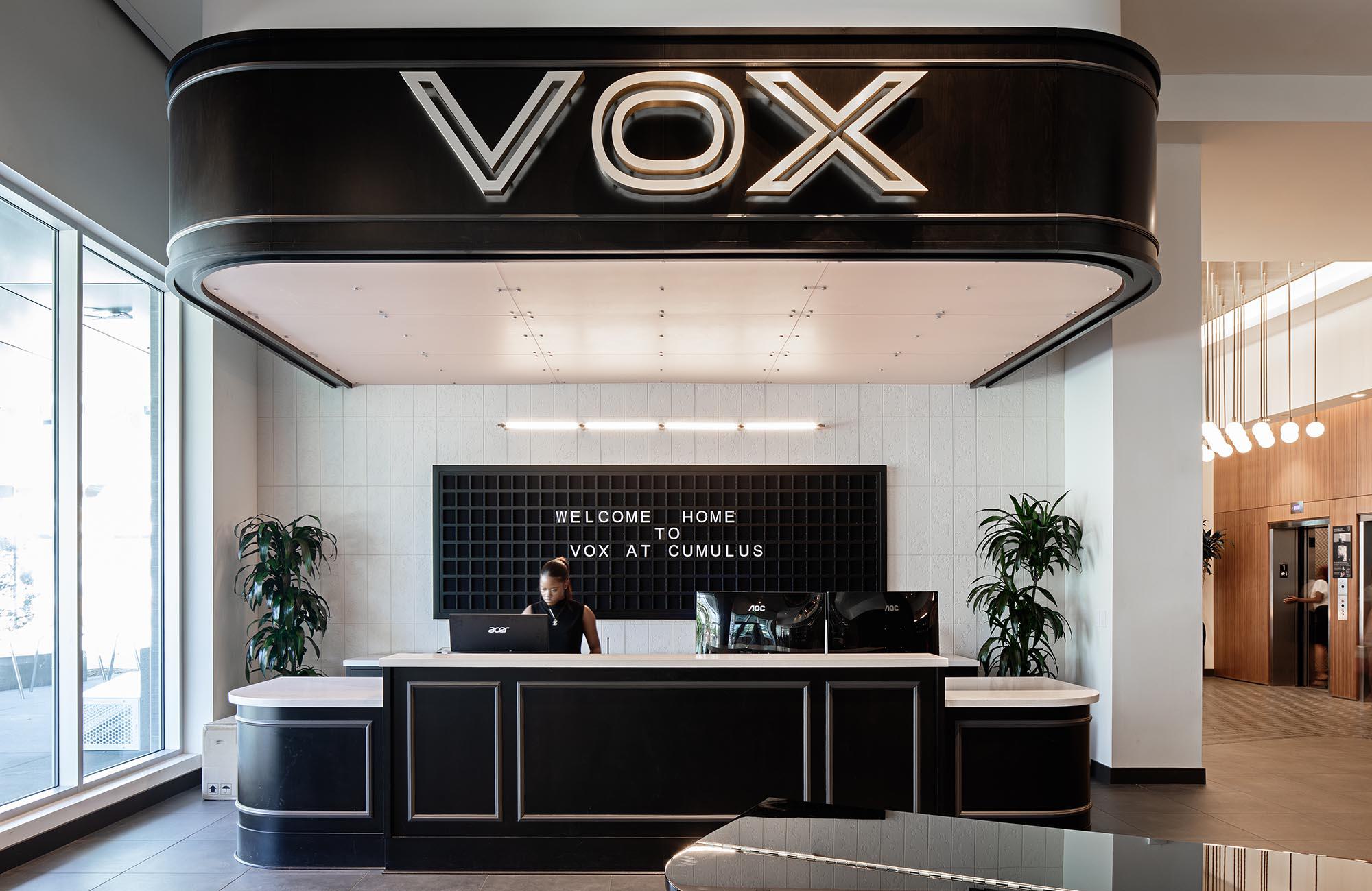 VOX Lobby, front desk receptionist with retro "flap sign" saying "Welcome Home to VOX at Cumulus"