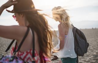  Two woman walking together on a beach at dusk
