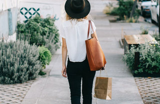 A woman walking with a small shopping bag