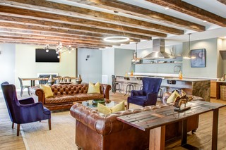Lounge with wingback chair, chesterfield sofas, a dining area, and a demonstration kitchen