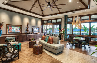 A common room with warm wood accents, tropical foliage, and various lounge and table seating arrangements