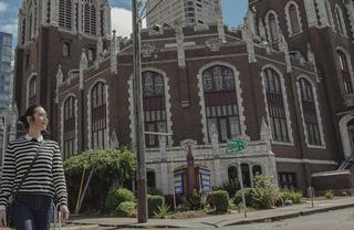 Woman walking in front of an old church.
