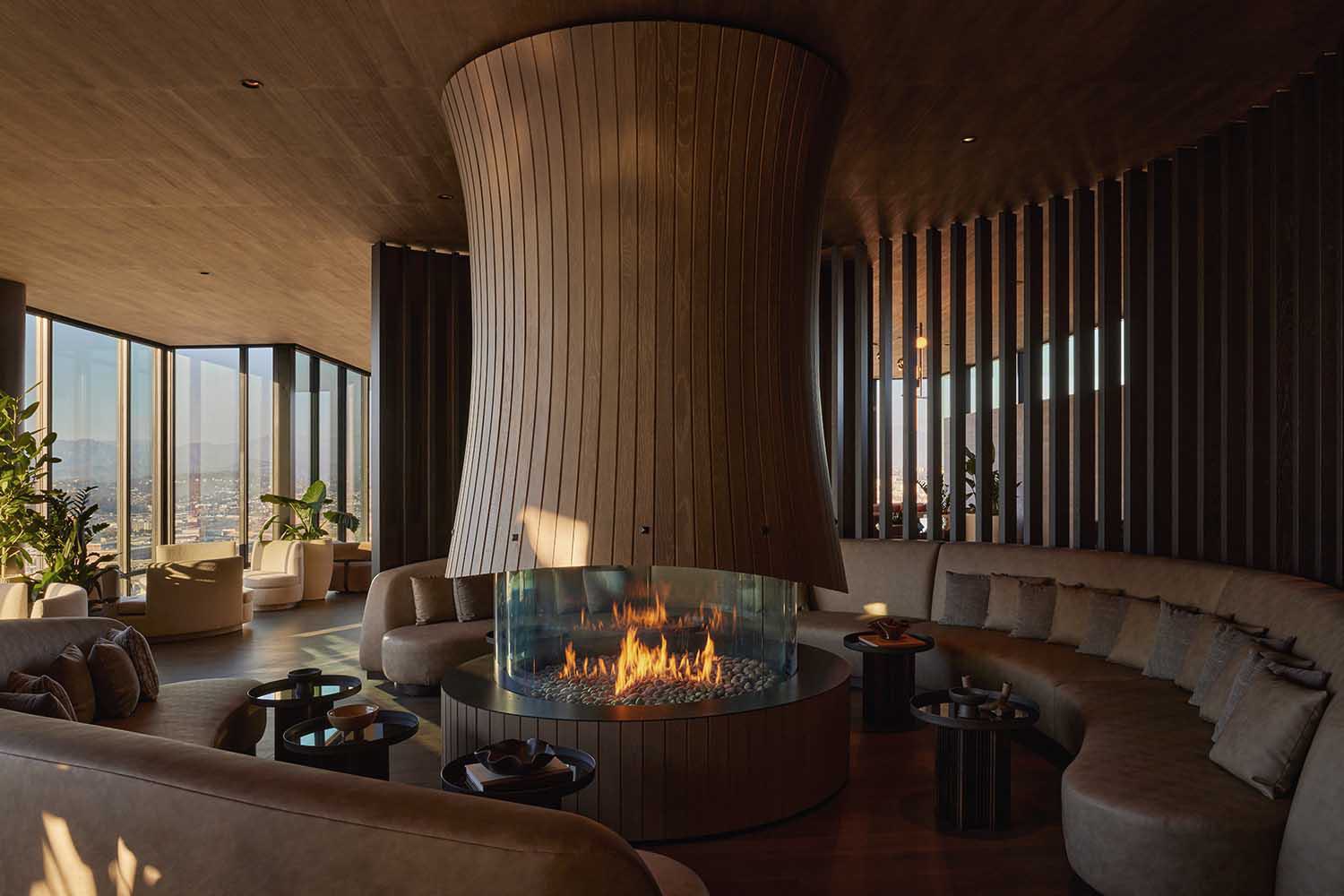 rooftop resident lounge with modern fireplace surrounded by wood paneling and downtown Los Angeles skyline views