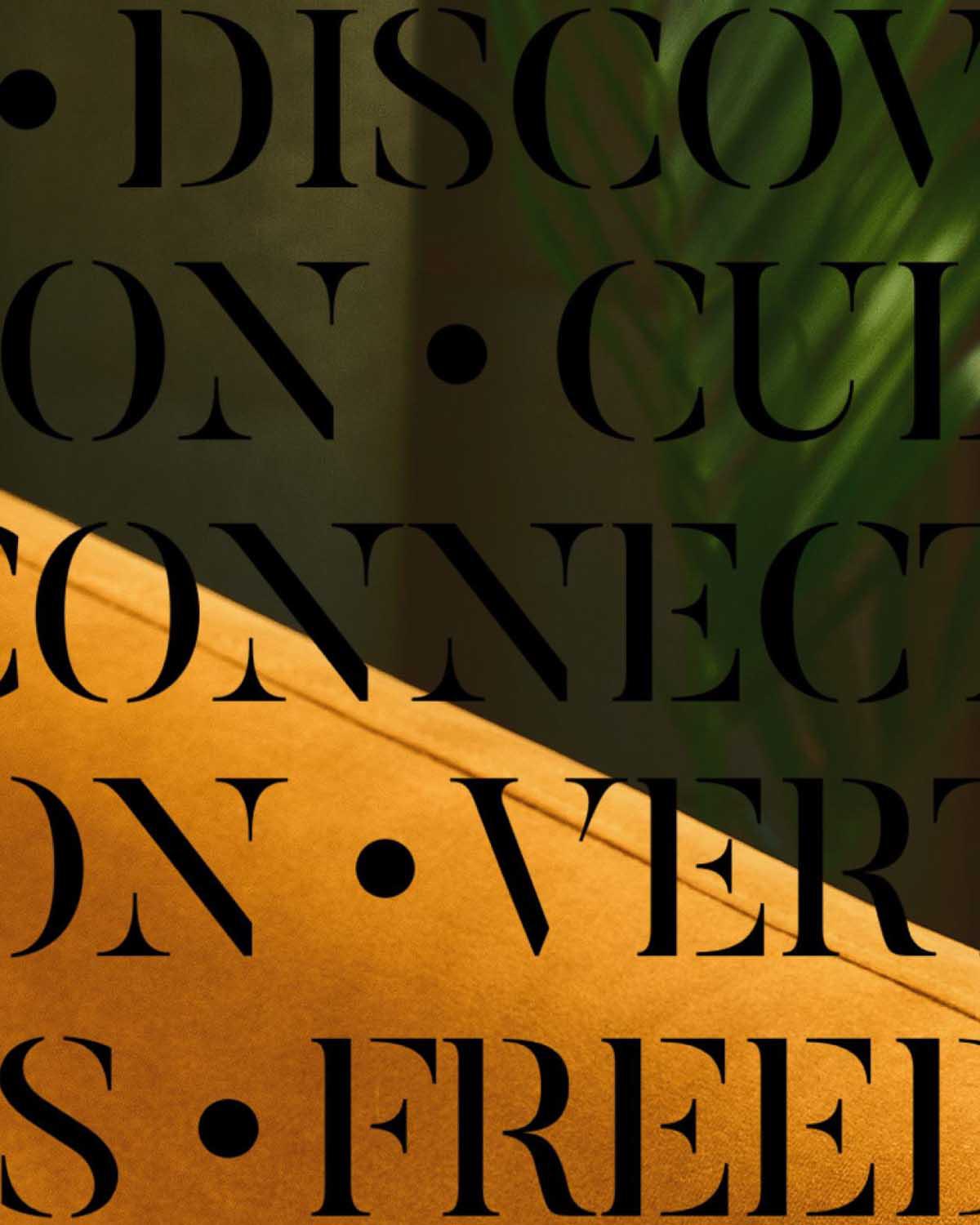 Close-up of mustard yellow upholstered seating with bold black typography overlaid, featuring words like “EXPRESSION,” “CONNECTION,” and “FREEDOM,” set against a moody interior with hints of greenery in the background.