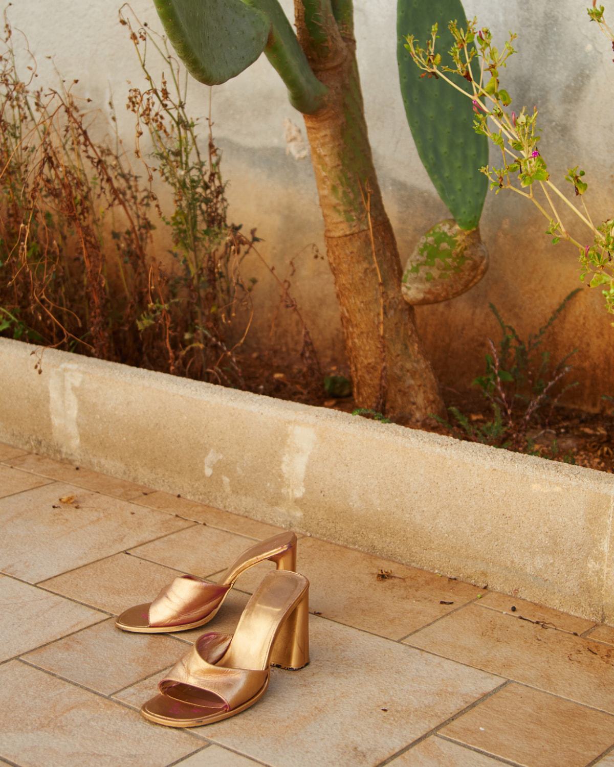 two gold high heeled shoes placed on a tiled floor
