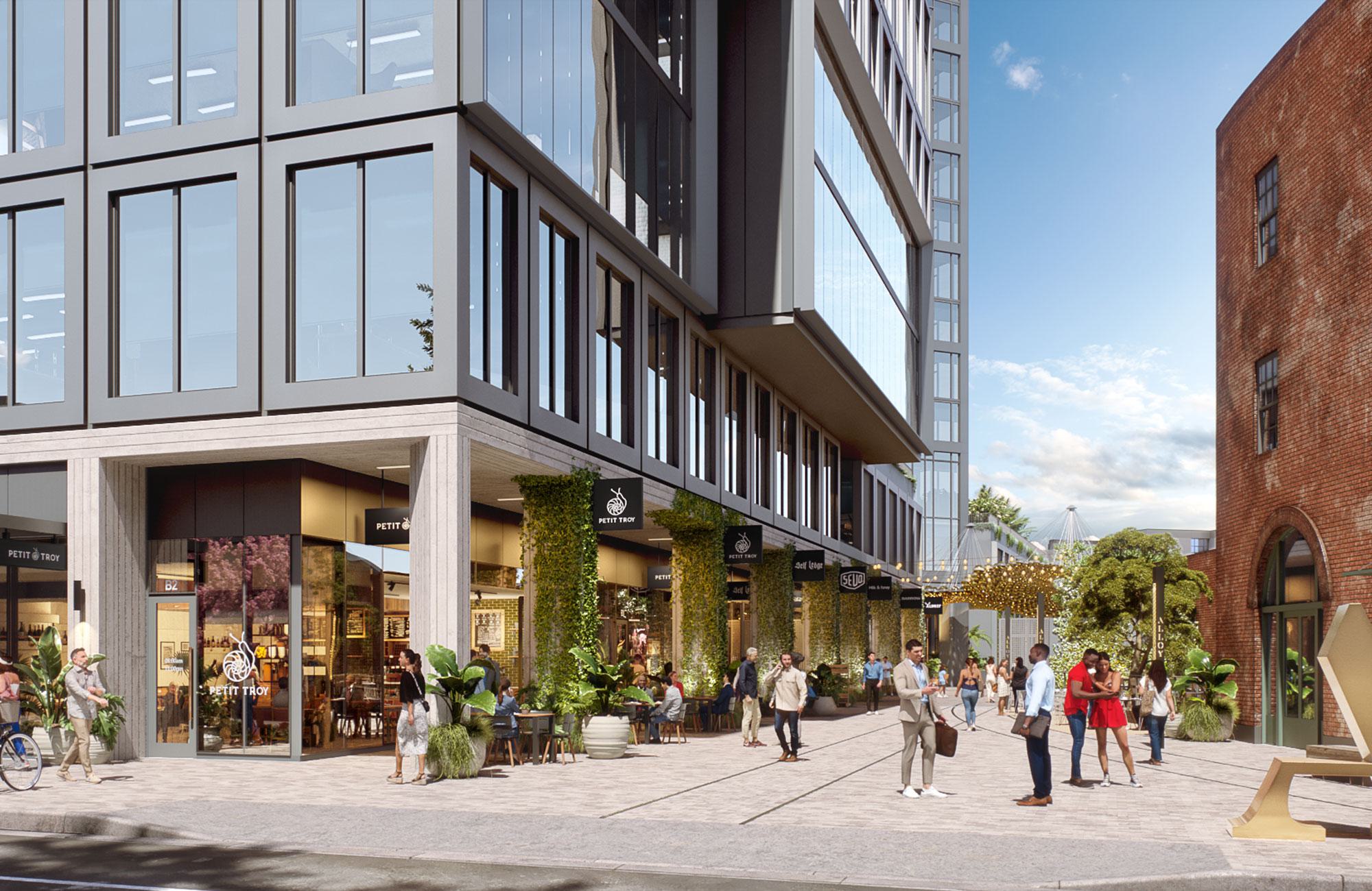Vibrant outdoor retail promenade at Alloy LA, featuring a striking canopy of golden discs, lush landscaping, and people gathering around shops and seating areas under warm evening light.