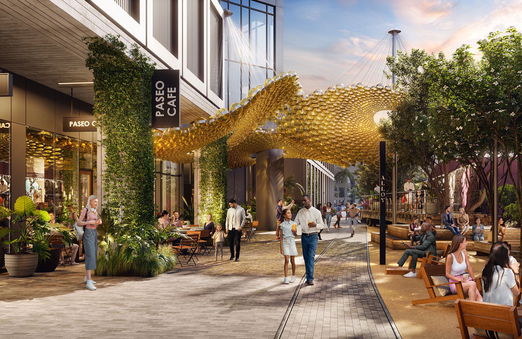 Vibrant outdoor retail promenade at Alloy LA, featuring a striking canopy of golden discs, lush landscaping, and people gathering around shops and seating areas under warm evening light.