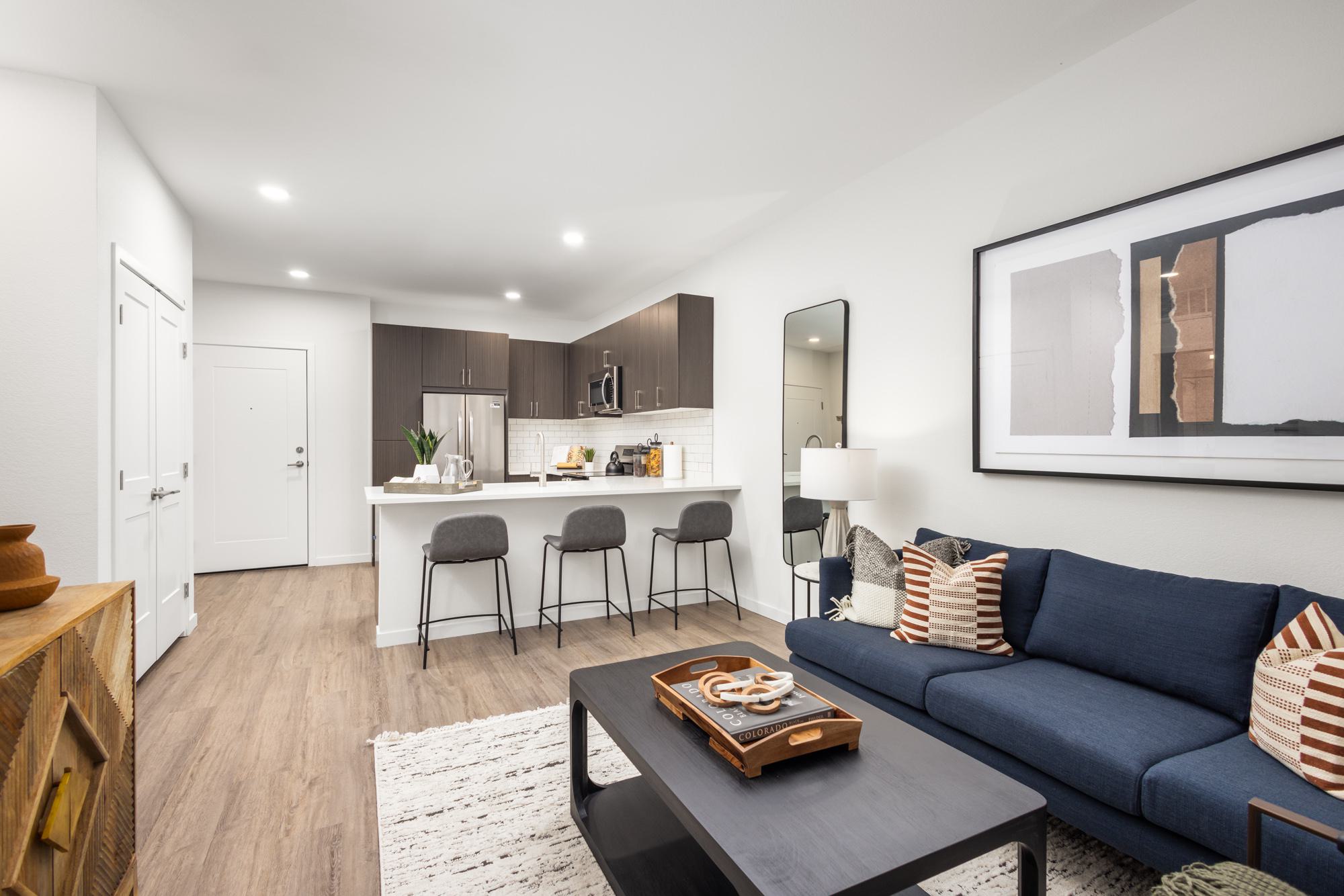 Living room with view to kitchen and dark brown cabinetry and light wood-style flooring