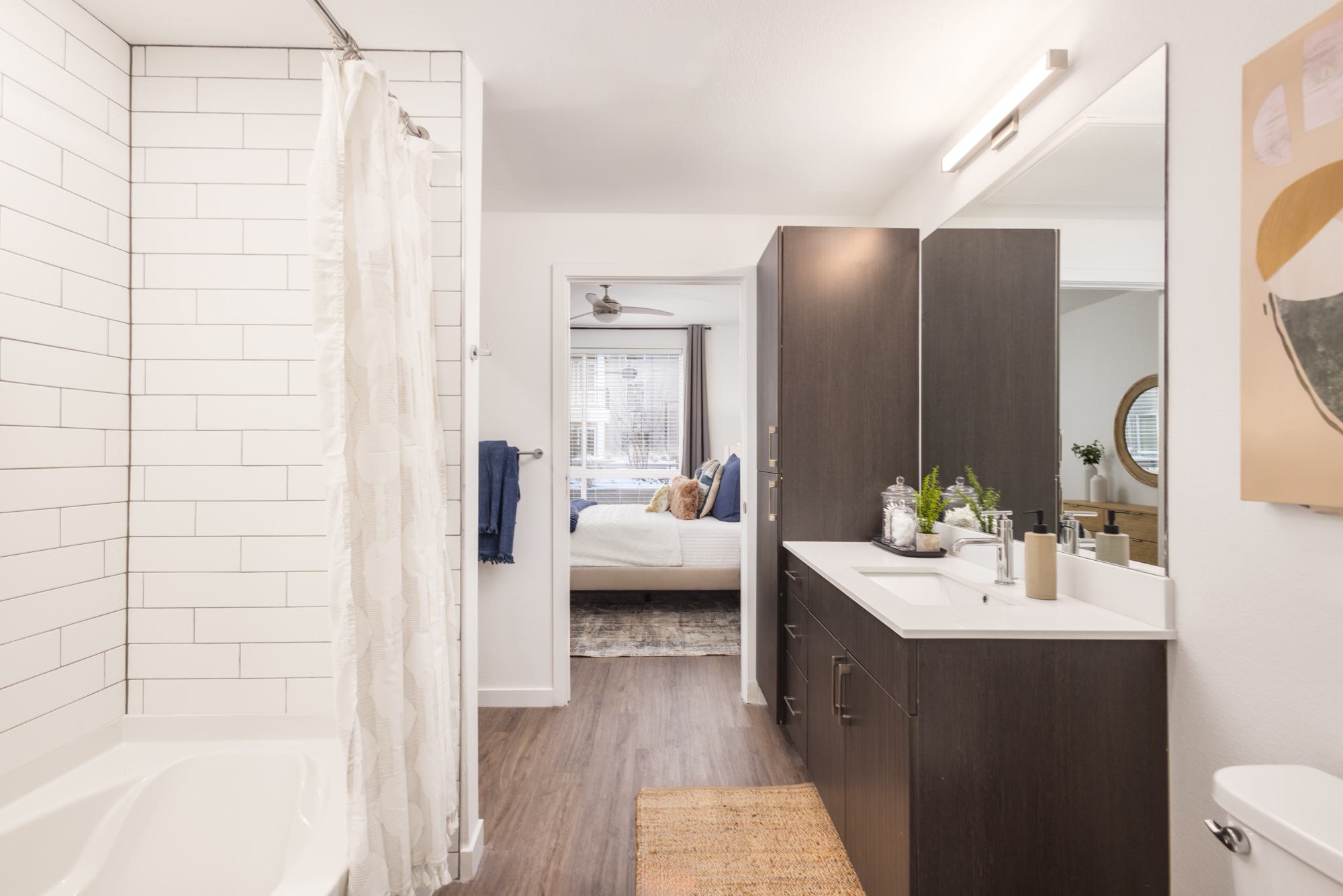 Bathroom with dark brown cabinets, large vanity and view to bedroom