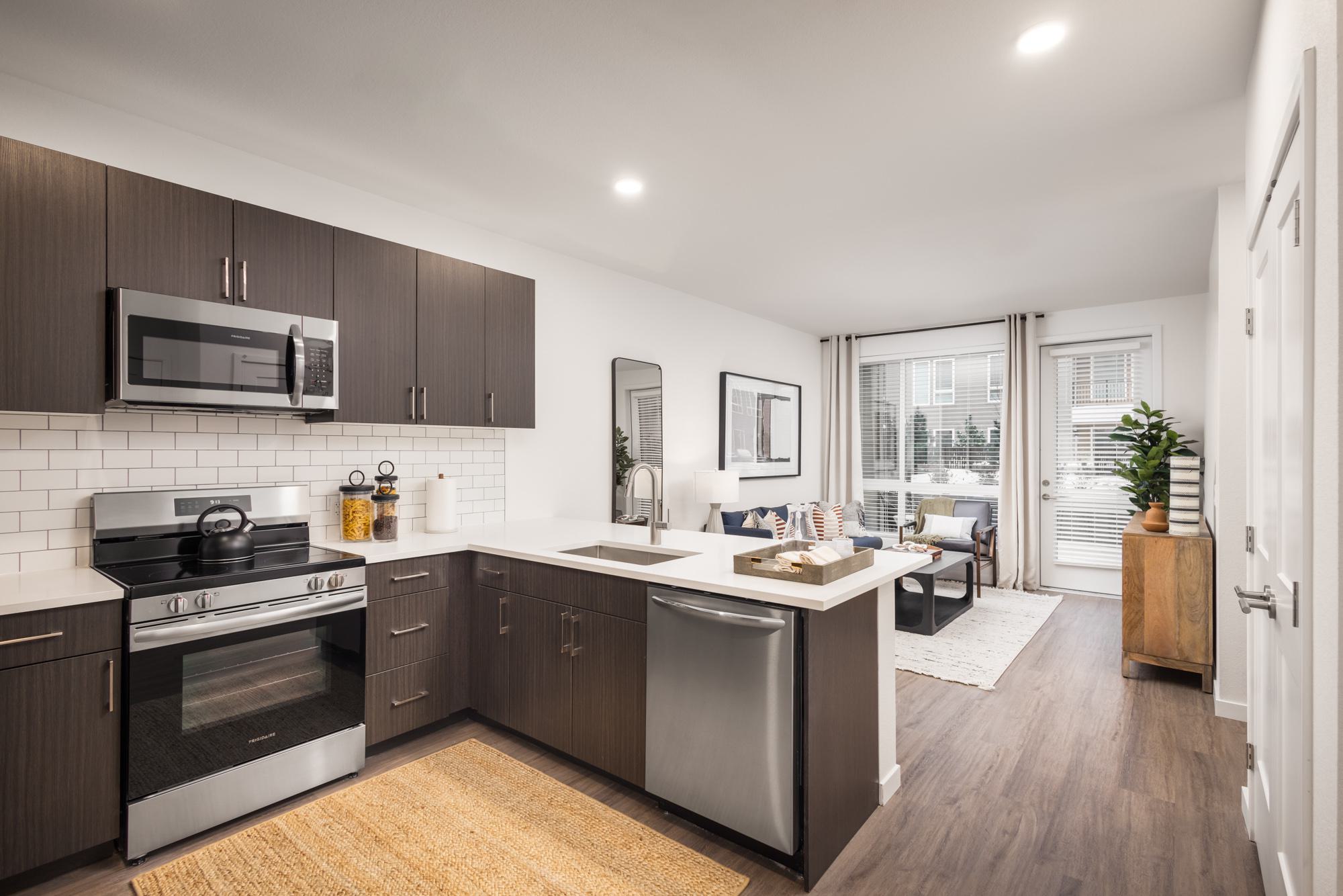 View from kitchen to living room with patio door and stainless steel appliances