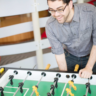 Student Playing Foosball in Community room at Sol at West Village Apts