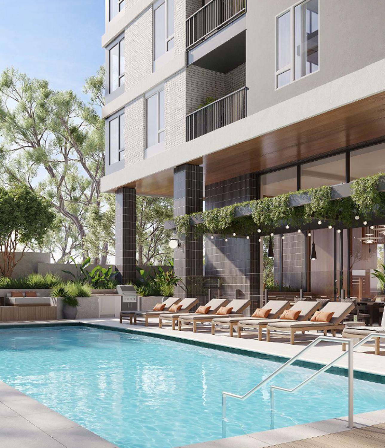 A modern outdoor pool deck featuring crisp loungers with terracotta pillows, lush landscaping, and shaded seating under string lights.