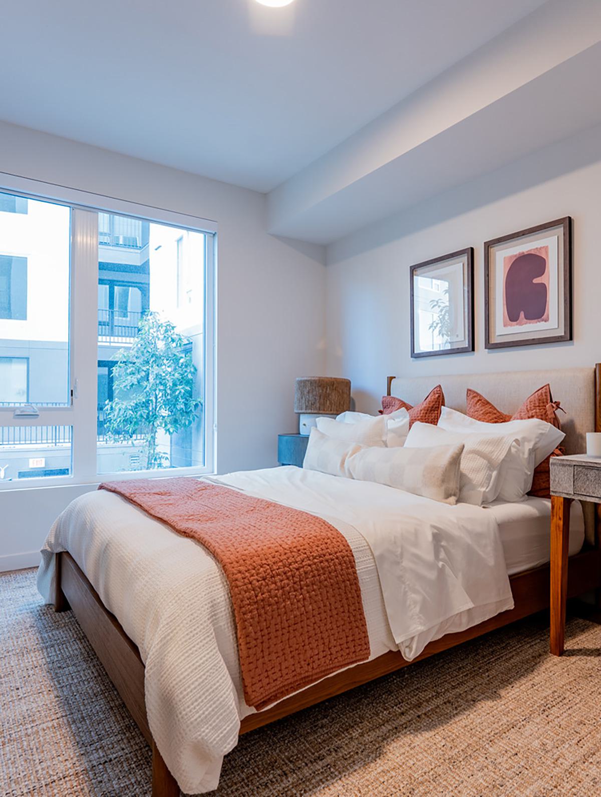 A light-filled living room with floor-to-ceiling windows offers sweeping views of Burlingame’s treetops, mid-rise buildings, and distant wooded hills. The vantage point captures a mix of residential greenery and the Bay Area’s suburban charm, extending toward the Santa Cruz Mountains.