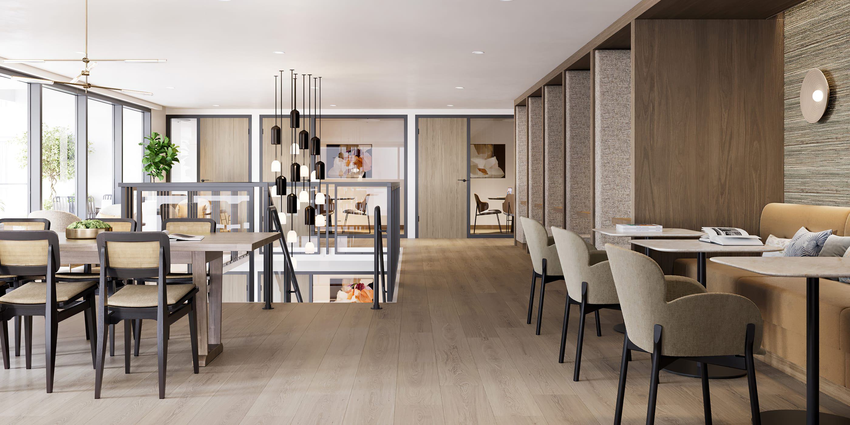 A bright, modern coworking and lounge space with wood floors, stylish pendant lighting, and a mix of communal tables and cozy booths. Floor-to-ceiling windows bring in natural light, while warm neutral tones and soft textures create a calm, productive atmosphere.