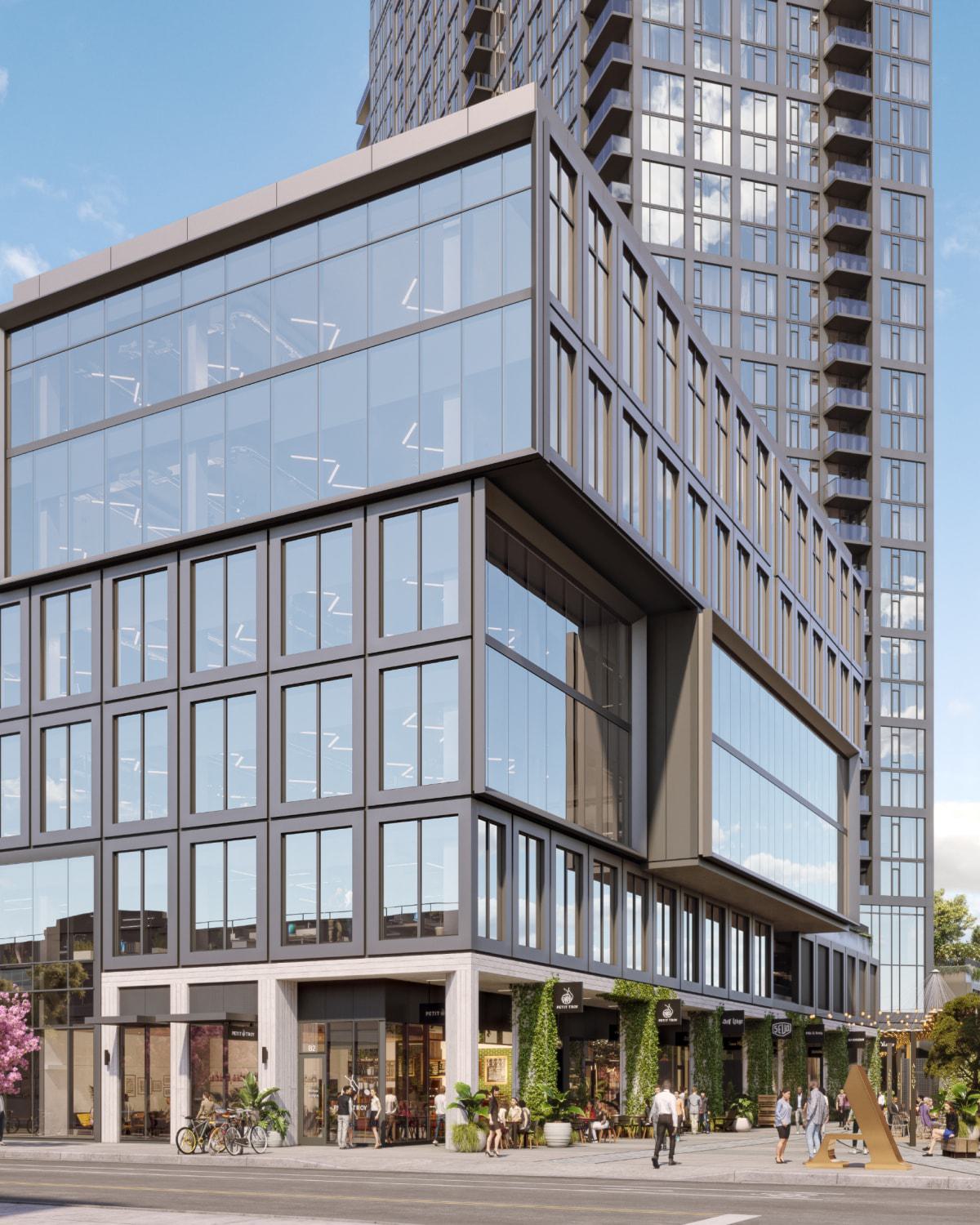 Modern mixed-use high-rise at Alloy LA with a cantilevered glass office section above retail storefronts. Ground-level greenery, pedestrians, and a golden sculpture animate the lively street corner.