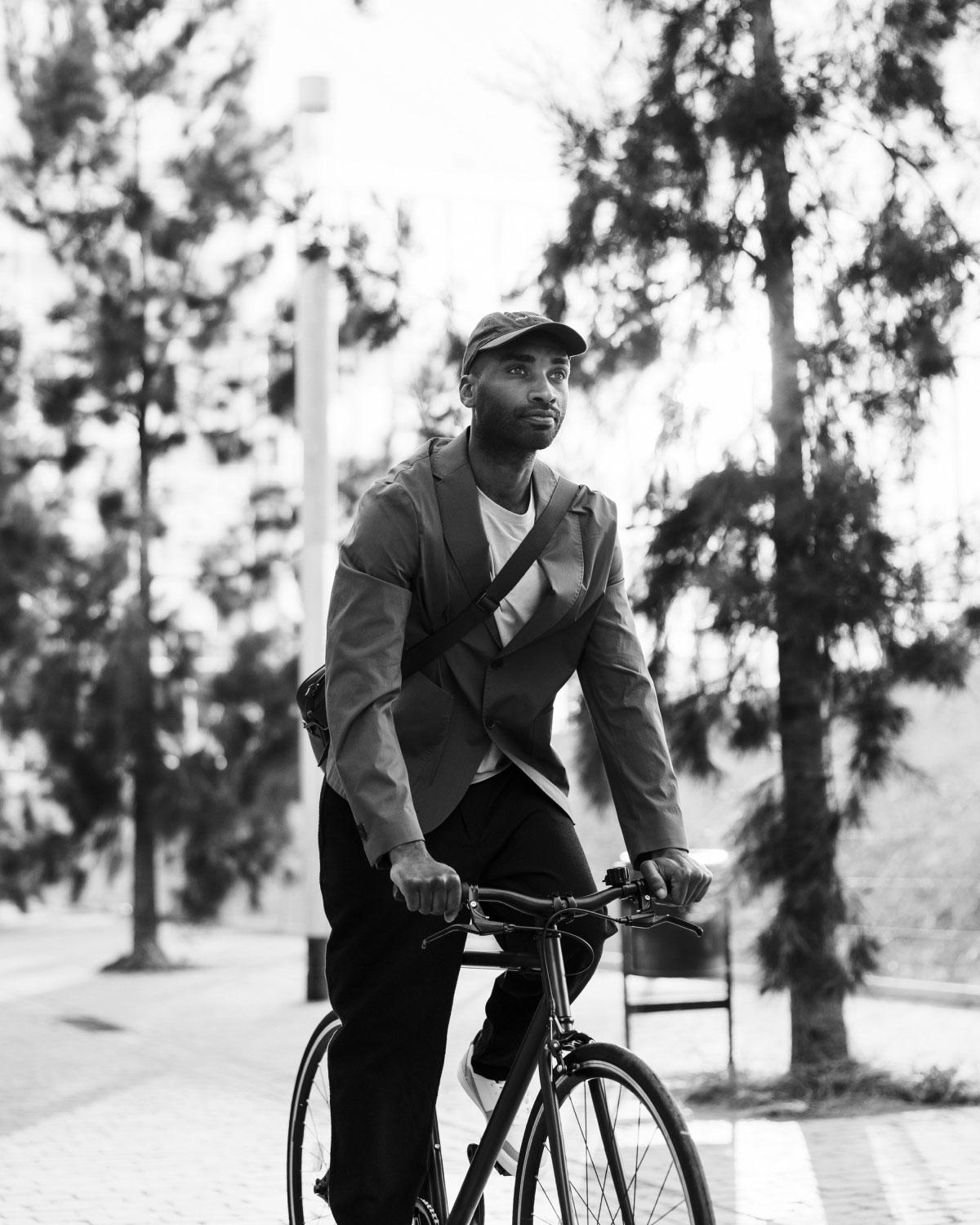 Black and white photo of a man riding a bicycle along a tree-lined path in Boston