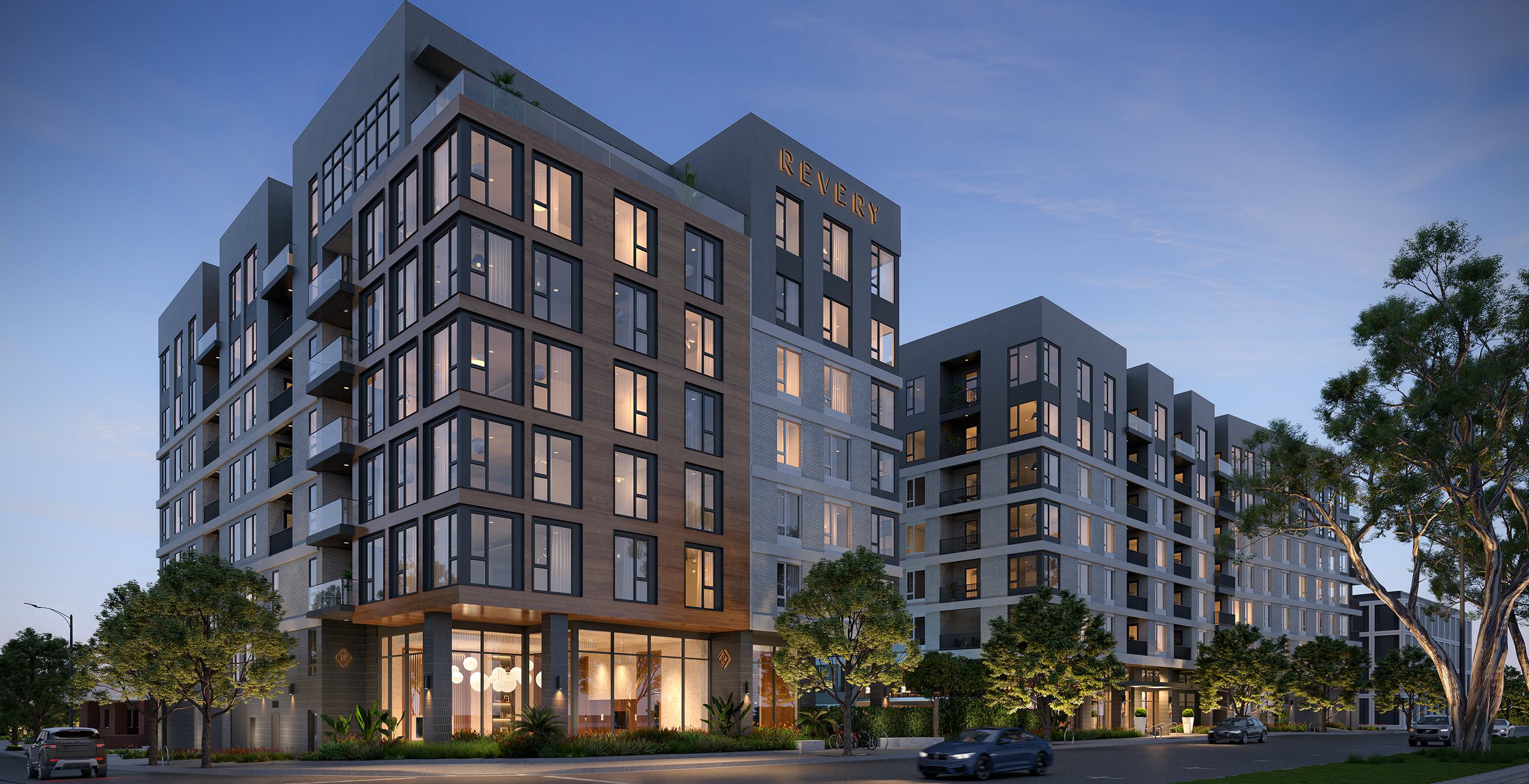 Modern,  mid-rise Revery apartment building at dusk, with sleek glass corner windows, warm interior lighting, and the name “REVERY” illuminated at the top. The design features clean lines, wood and brick textures, and landscaped trees lining the sidewalk for an inviting urban presence.