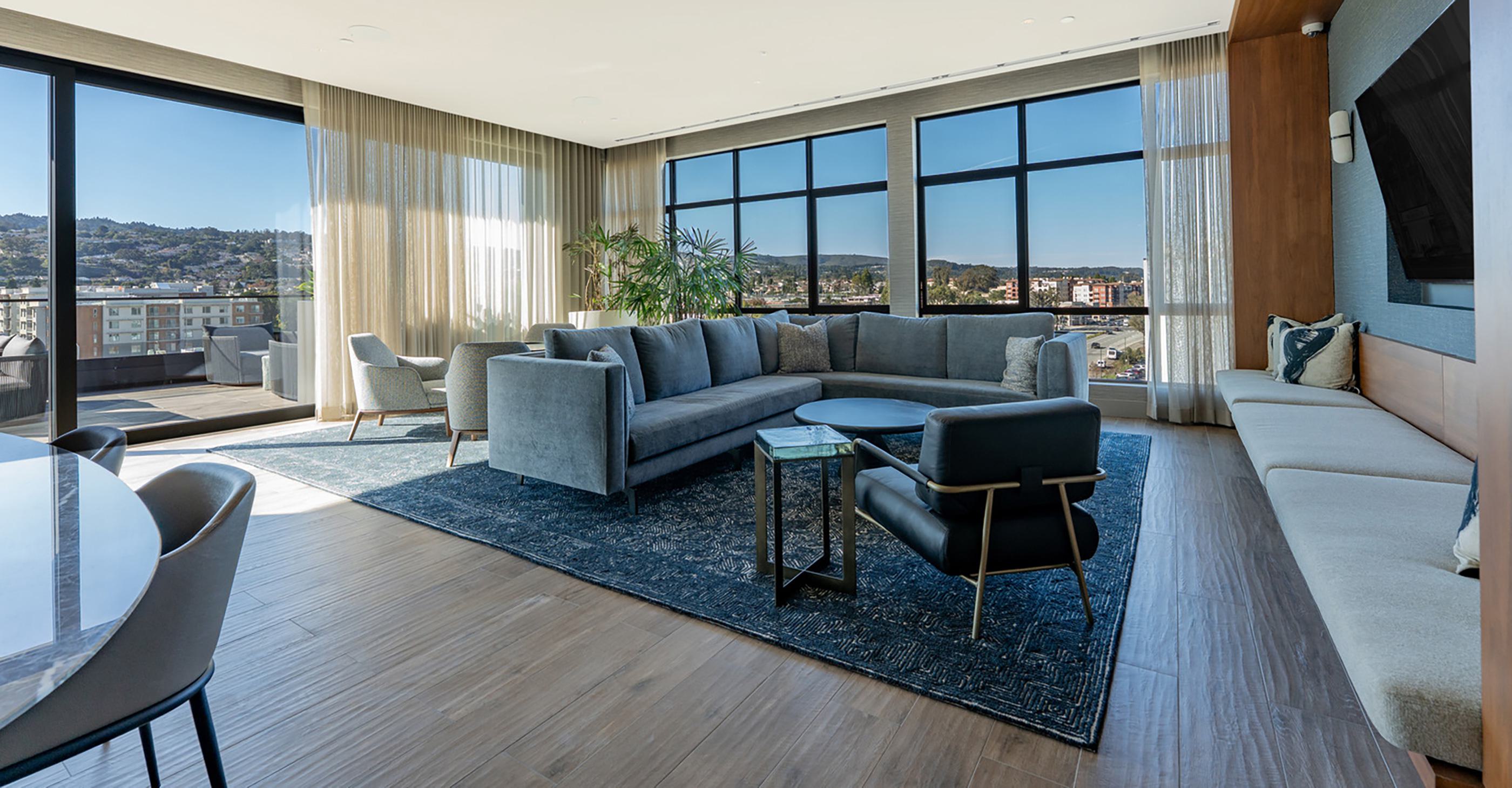 This bright, contemporary living room opens to a private balcony with sweeping views of the San Francisco Bay. Large windows frame the water and distant East Bay hills.