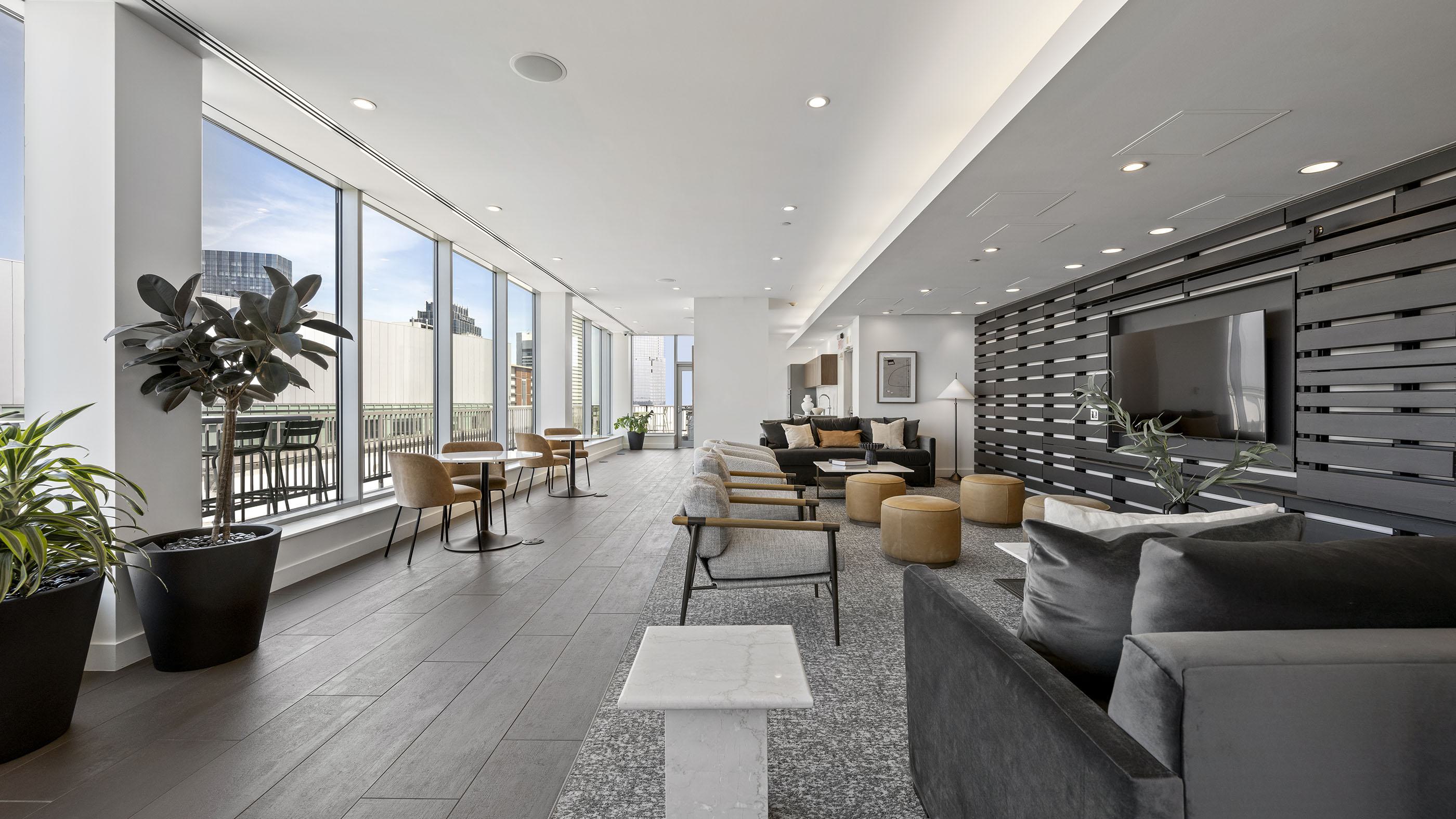 Bright rooftop SkyLounge with floor-to-ceiling windows, modern seating areas, and downtown Boston skyline views.