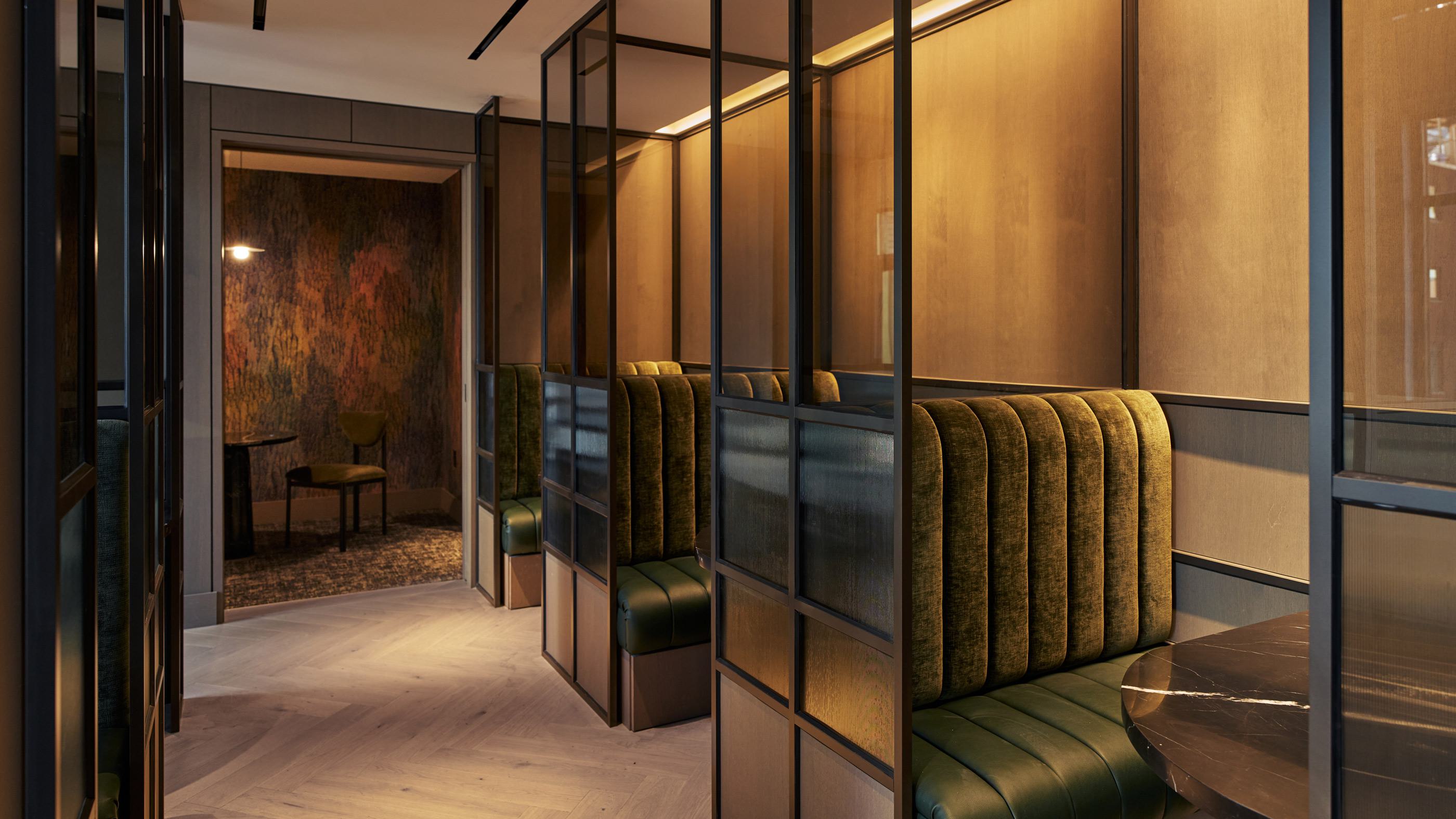 sophisticated coworking lounge featuring plush curved seating, warm wood paneling, built-in bookshelves, and abstract artwork, creating a stylish and inviting workspace.