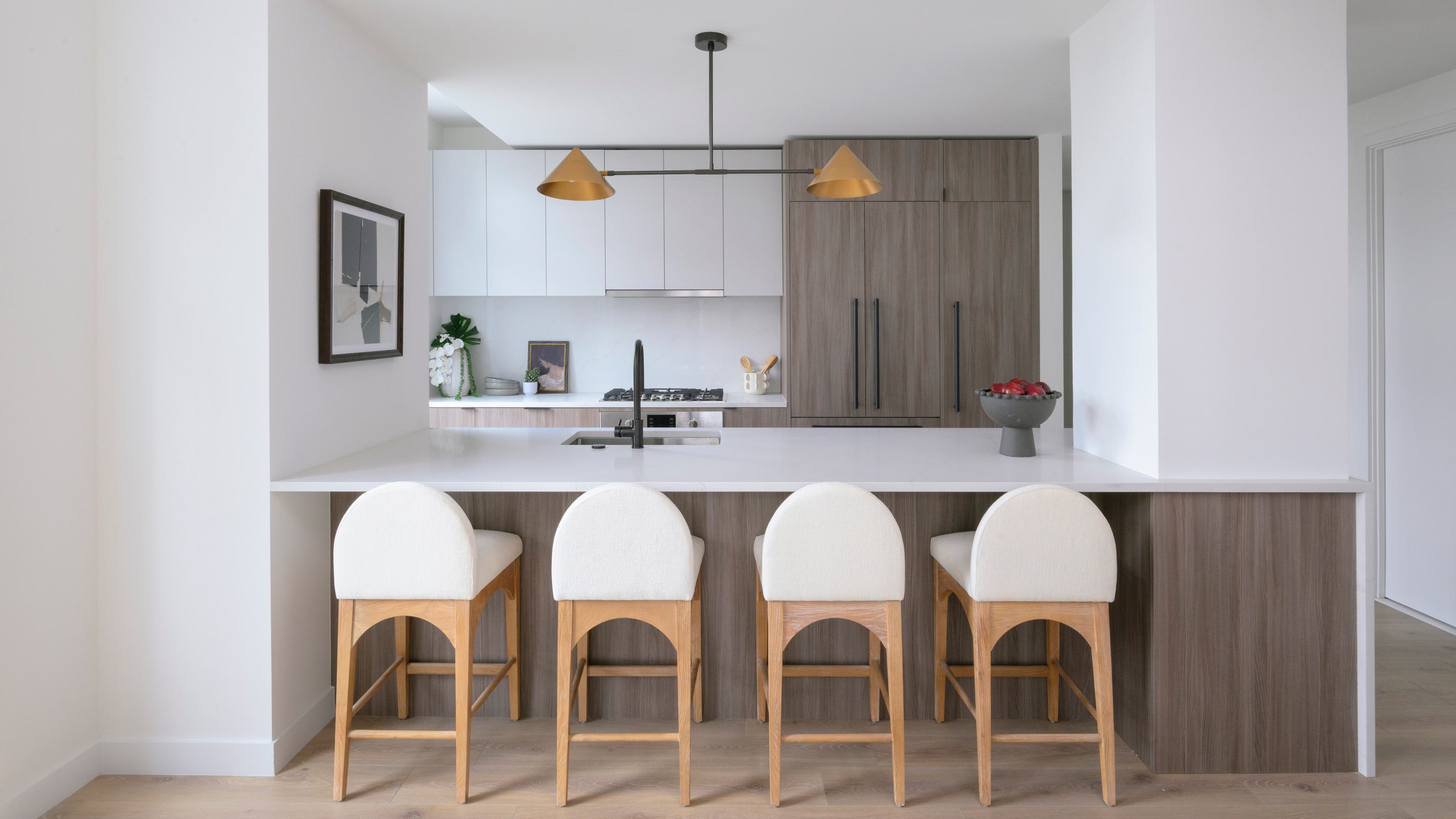 sophisticated open-concept kitchen and dining area featuring a marble island with bar seating, sleek cabinetry, warm wood accents, and floor-to-ceiling windows with city views.
