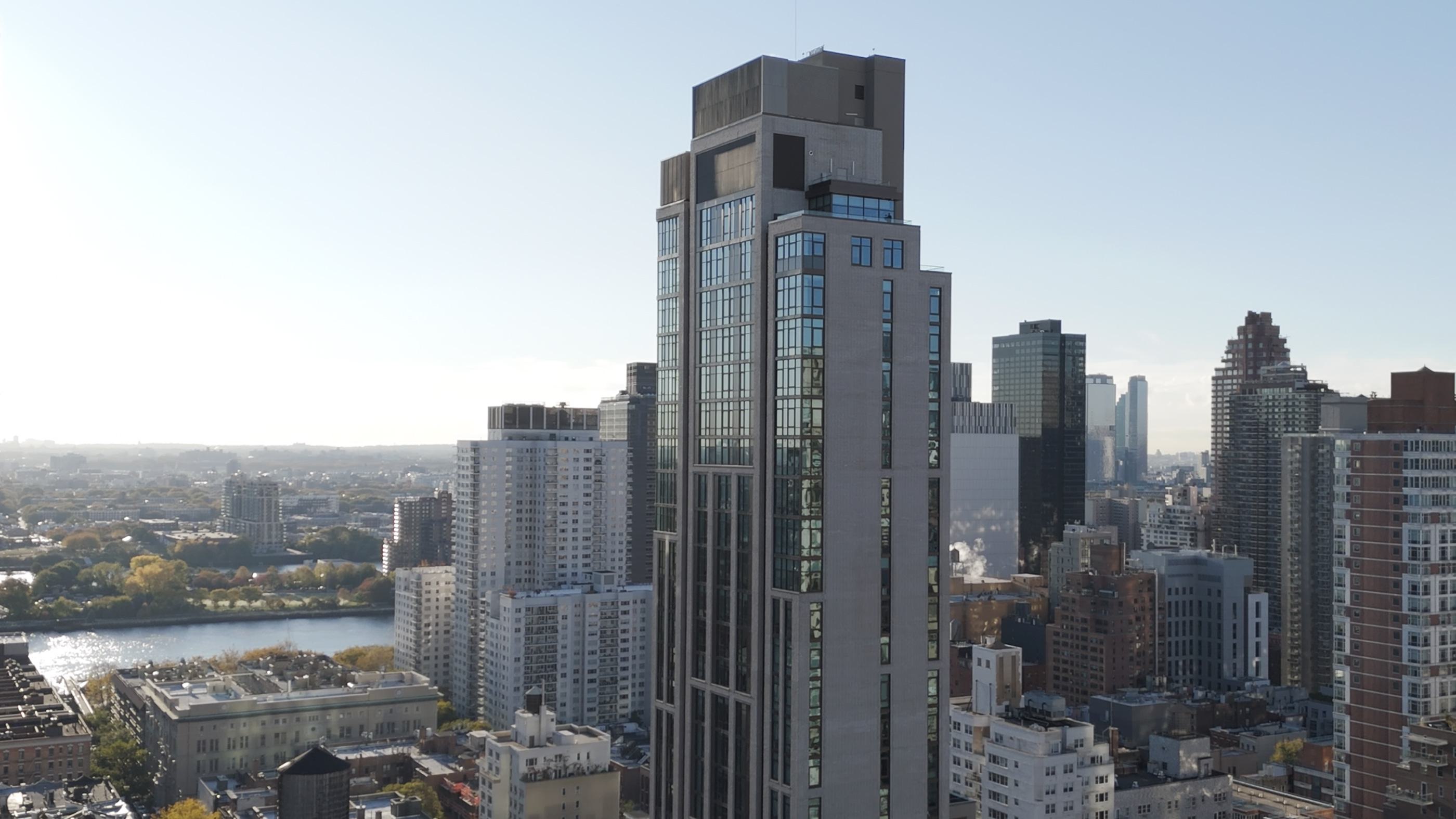 exterior of striking new Maison 78 high-rise building with modern glass and metal accents, set against a backdrop of a nyc city skyline 