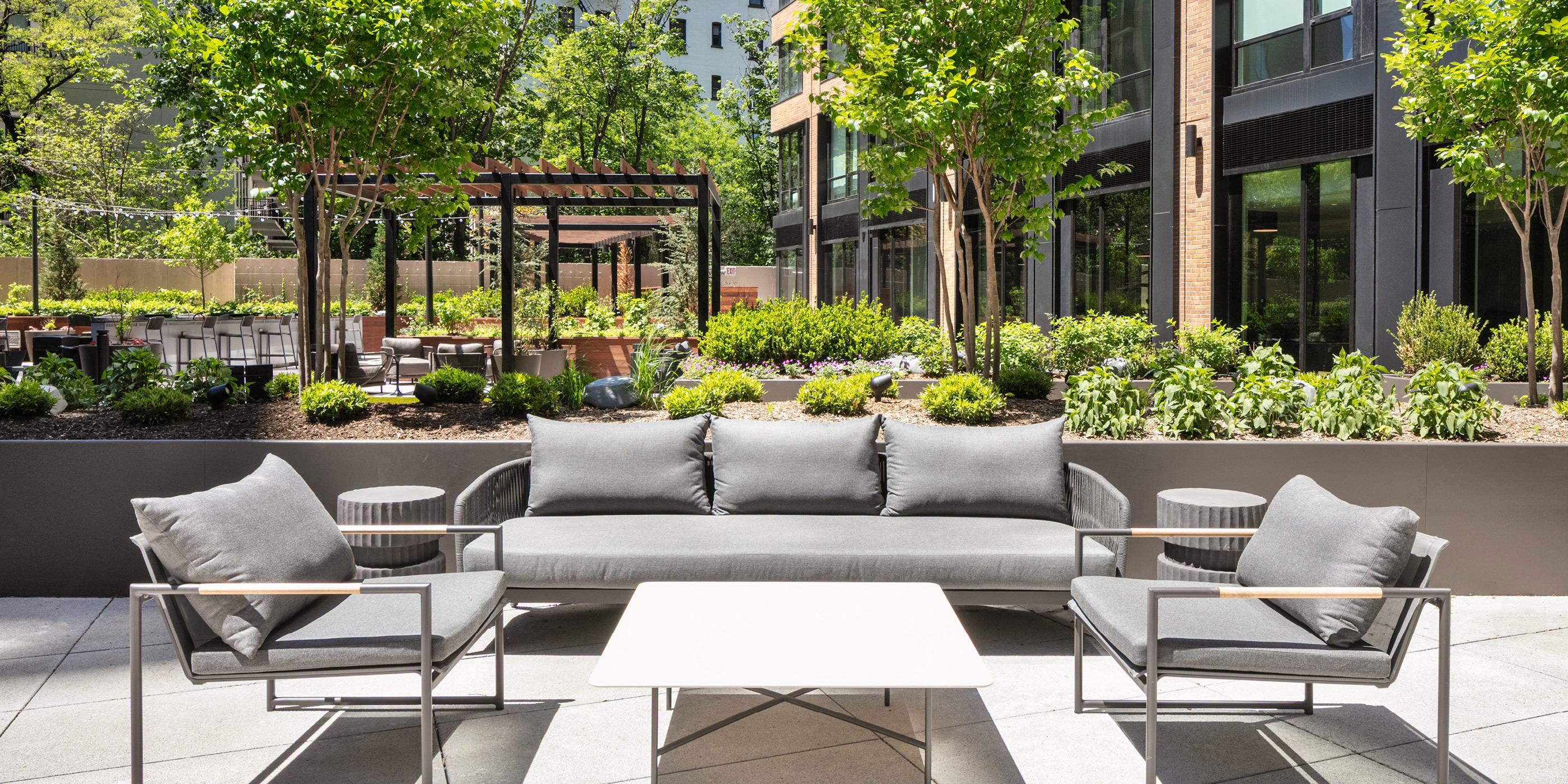 private interior courtyard at loden with lush greenery thoughtful planned spaces with chairs and tables, outdoor grills, a variety of different seating areas, walking paths, and shaded wooden pergolas, 