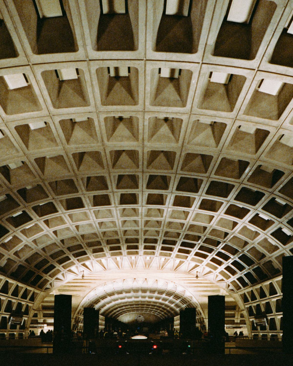 Underground Washington, DC Metro station with iconic Brutalist vaulted ceiling and geometric coffered design, illuminated in warm lighting